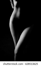 Black and White Beautiful woman body. Fashion art studio portrait of elegant naked lady with shadow on her. Female stomach isolated on black background. Erotic pose low key shoot