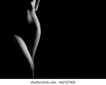 Black and White Beautiful woman body. Fashion art studio portrait of elegant naked lady with shadow on her. Female stomach isolated on black background. Erotic pose low key shoot