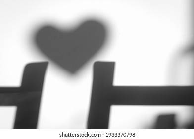 Black And White Blurred Shadow Of A Heart Between Two Chairs. Light From The Morning Sun On Nude Wall. Heart Silhouette.