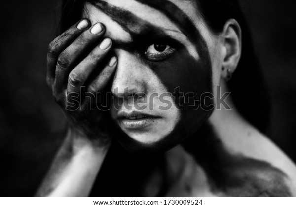 Black and white body art on a beautiful girl. Black\
and white portrait of a beautiful young girl with a pattern on the\
face. Art body painting. Girl holds her hands over face, eyes,\
lips.