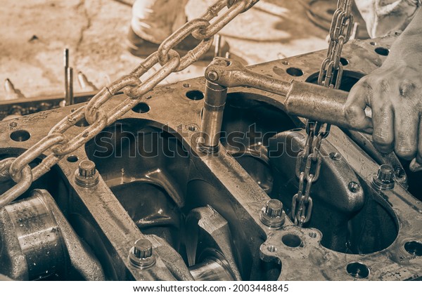 Black and White Car Mechanic or Auto\
Mechanic Using Breaker Bar Loosen Cylinder Block\
Bolt