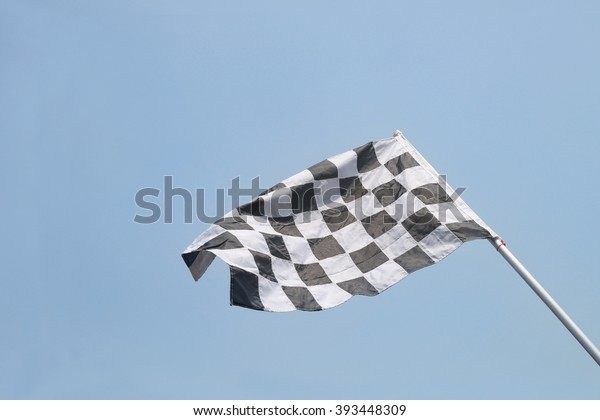 Black\
and white checkered flag.on blue sky\
background.