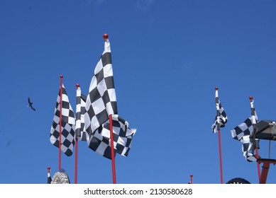 Black and white chequered flags against a clear deep blue sky taken at a fairground 