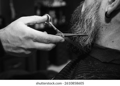 Foto vintage clásica en blanco y negro, primer plano, barba de barbero con cortadora eléctrica, tijeras para el cabello en la barbería moderna. Servicios de aseo y cuidado de la barba de los hombres del Profesional, foco selectivo