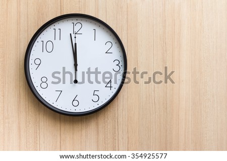 black and white clock shown almost mid day or mid night time on light wooden wall
,free space for text 
concept : countdown for new year 
