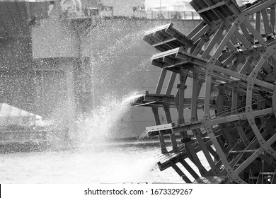 black and white close up of an old paddle wheel on the river
