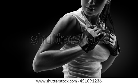 Black and white close up portrait of fitness athletic young woman in sports clothing showing her well trained body, six pack, perfect abs, shoulders, biceps, triceps and chest, deltoid muscle.