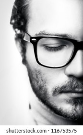 Black & White Close Up Portrait Of Young Man In Glasses And A Half Face In Studio On A Light Background