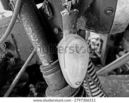 Black and white close up of a rusty and broken vintage motorcycle turn signal. Monochrome retro motorbike part with heavy rust texture and dusty lens for industrial garage grunge concept.