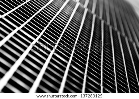 Black and white close up of a sidewalk subway grate with shallow depth of field.