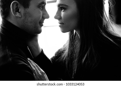 Black and white close-up photo on which beautiful couple in love looks at each other with love and smiling