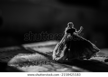 A black and white closeup shot of a female toy on a fabric su