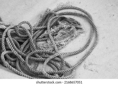 Black And White Closeup Shot Of Shabby Coil Of Nautical Rope Tangled On The Bottom Of A Fishing Boat Hull.