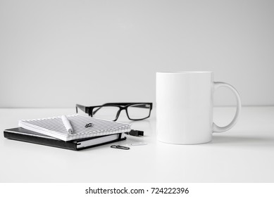 Black and white coffee mug mock up with notebooks, pen and eyeglasses on work desk.  - Powered by Shutterstock