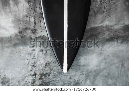 Black and white color surf board on gray concrete wall background. Contemporary interior design of cafe in minimalist style. Dark shabby texture.