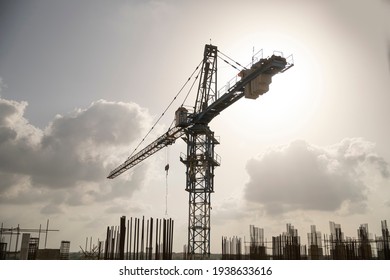 black and white construction site including several cranes working on a silhouette complex, with cloudy background