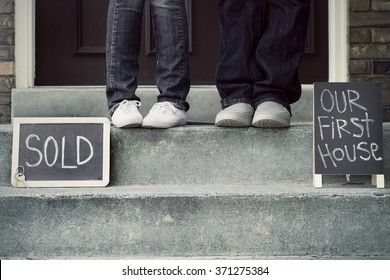 Black And White Couple On New Home Doorstep With Sold Sign And First House Sign