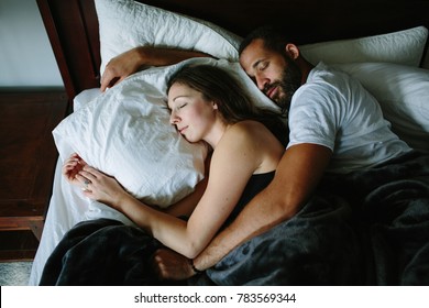 Black And White Couple Sleeping And Holding Each Other In Bed