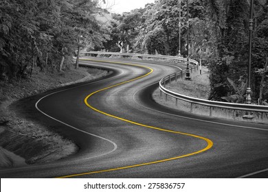 Black and white curve way of asphalt road in nature with yellow line.