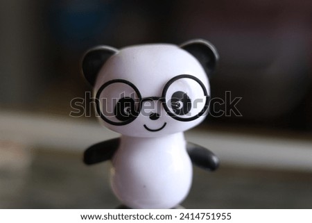 A Black and White cute solar powered panda wearing black glasses toy on a shelf, selective focus 