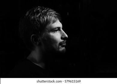 Black And White Dramatic Portrait Of A Handsome Confident Man, 30-35 Years Old. Profile Headshot In Low Key Isolated On Black Background. Horizontal Copy Space.