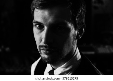 Black And White Dramatic Portrait Of A Handsome Confident Man, 30-35 Years Old. Strong Face Looking To The Camera, Half Face In Shadow. Serious Headshot Photo.