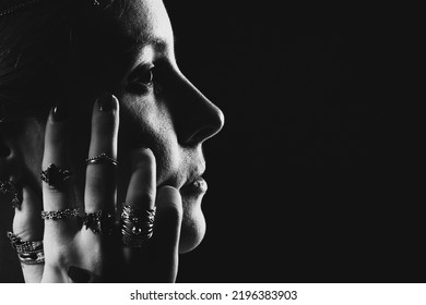 Black And White Dramatic Profile Portrait Of A Young Woman Wearing Occult Jewelry In Low Key.