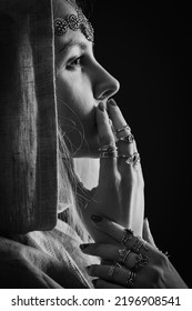 Black And White Dramatic Profile Portrait Of A Young Woman Wearing A Hood And Occult Jewelry.