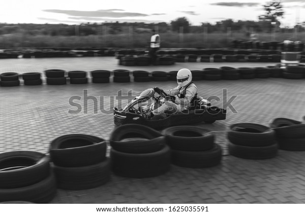 Black and white. A driver in\
gear and helmet drives a racing car. In action. Go karts racing,\
sreet karting, rent. extreme sport. fun entertainment for\
drivers