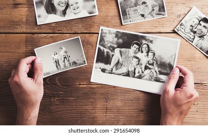 Black And White Family Photos Laid On Wooden Table Background.