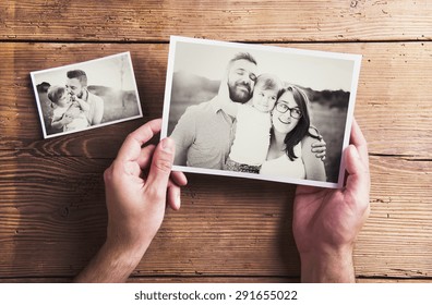 Black And White Family Photos Laid On Wooden Floor Background.