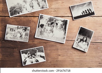 Black And White Family Photos Laid On Wooden Floor Background.