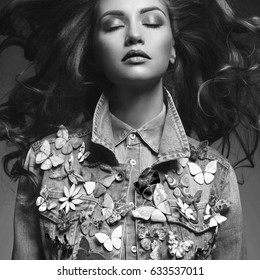 Black and white fashion studio photo of young beauty woman  with a lot of brooches on her jeans jacket. Denim clothes. Jeans trend. Magnificent hair