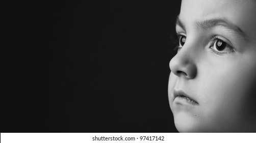 black and white girl's face on black background is thinking and looking away