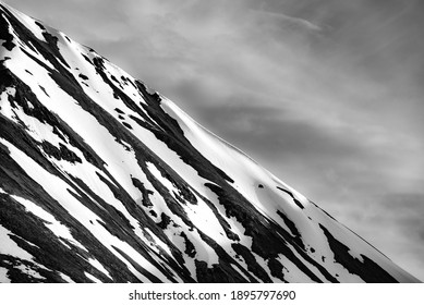 Black and white grayscale of snowy capped mountains in northern Canada on a cloudy, grey sky day. Close up view of snow running down mountain side.  - Powered by Shutterstock