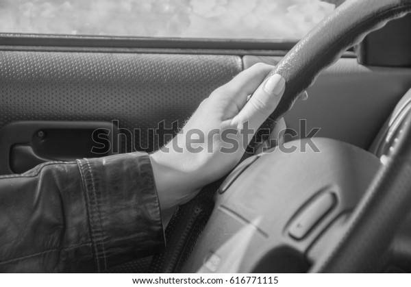 black and white, the hand on the wheel of a car on a\
Sunny day.