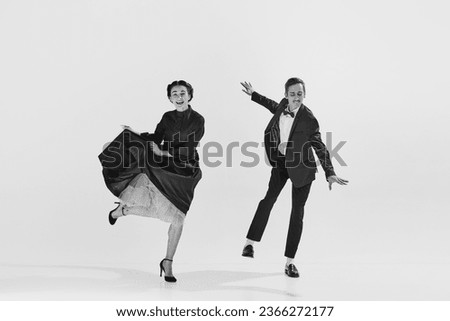 Black and white. Happy, positive, smiling young people, man and woman in elegant clothes dancing lindy hop. Concept of hobby, retro dance, vintage style, choreography, beauty. Monochrome art. Ad