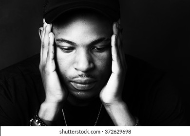 Black And White High Contrast African American Male With His Hands To His Face. Close Up Head Shot Portrait.