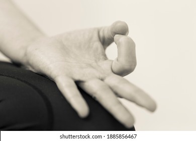 Black and white horizontal closeup of hand gesture or mudra with palm up, directing energy and maintaining focus during meditation by bringing tip of thumb and index fingers together, forming a circle