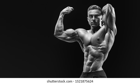 Black And White Horizontal Portrait Of Body Builder With Muscular Physique Looking Forward. Masculine Young Fitness Male Model Posing Shirtless Bodybuilder With Muscular Physique Showing Biceps