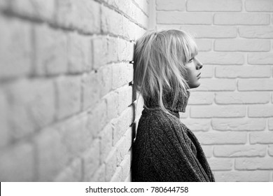 Black And White Horizontal Shot Of A Young Woman Wearing Warm Winter Sweater Leaning On The Wall Resting At Home Copyspace Sadness Pity Unhappy Expressive Emotional Depression.