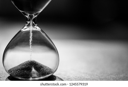 Black And White Hourglass With Dark Background For Copy Space. Concept For Business Deadline, Urgency And Running Out Of Time.