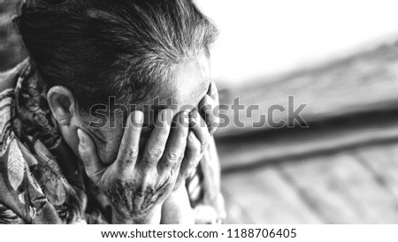 Black and white Image of 60s or 70s  Asian elderly woman facepalm or cover her face by her hands .She may suffering from illness or depress.She looks pain or sick or crying.Sad elderly concept.