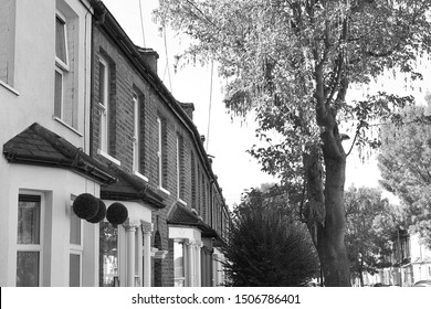 Black And White Image Of Beautiful Victorian Terraced Houses Set On Tree Lined Street In Stratford, London.  