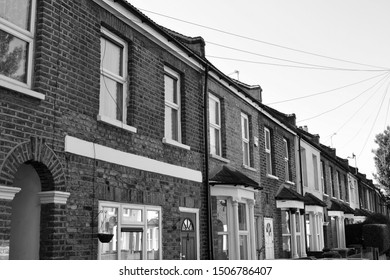 Black And White Image Of Beautiful Victorian Terraced Houses Set On Tree Lined Street In Stratford, London.  