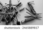 Black and white image of blades and screws of steel multi-tool VS pile of hand tools dumped in disarray

