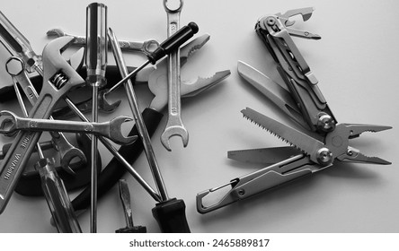 Black and white image of blades and screws of steel multi-tool VS pile of hand tools dumped in disarray
