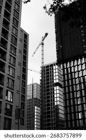 Black and white image capturing intensity and hard work of construction laborers. Construction crane symbolizes demanding physicality of job, with facing challenges of construction process