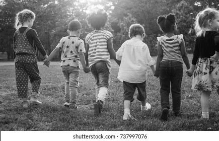 Black And White Image Of Children Walking At The Park