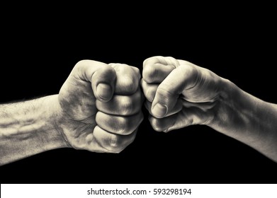 black and white image close up clash of two fists on black background. Concept of confrontation, competition etc.